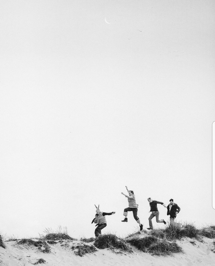 Friends jumping together across a sand dune